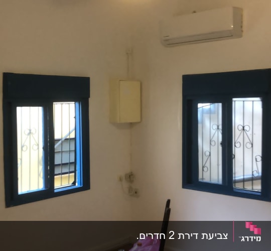 חדר צבוע בלבן עם רצפת פרקט וציוד צביעה במרכז החלל